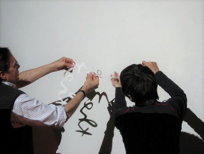 two people holding a cursive paper cutout